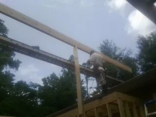 Carpenter setting a ridge beam over a new addition frame — Ice Dam Removal by Roofing Brothers in Loganton