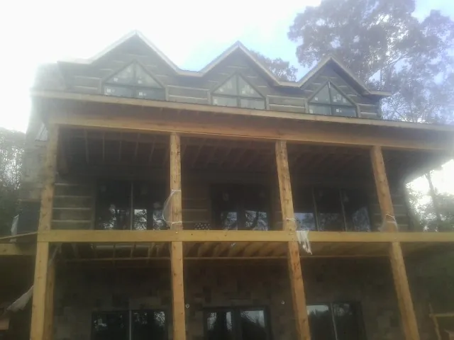 Dormers and porch framing on a large log home under construction — Roof Coating work by our crew in Loganton