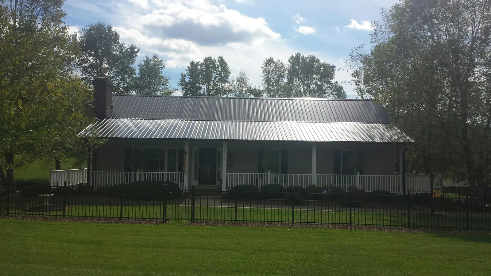Gray metal roof on a brick ranch with a full width front porch — Gutter Guard Installation work by our crew in Loganton
