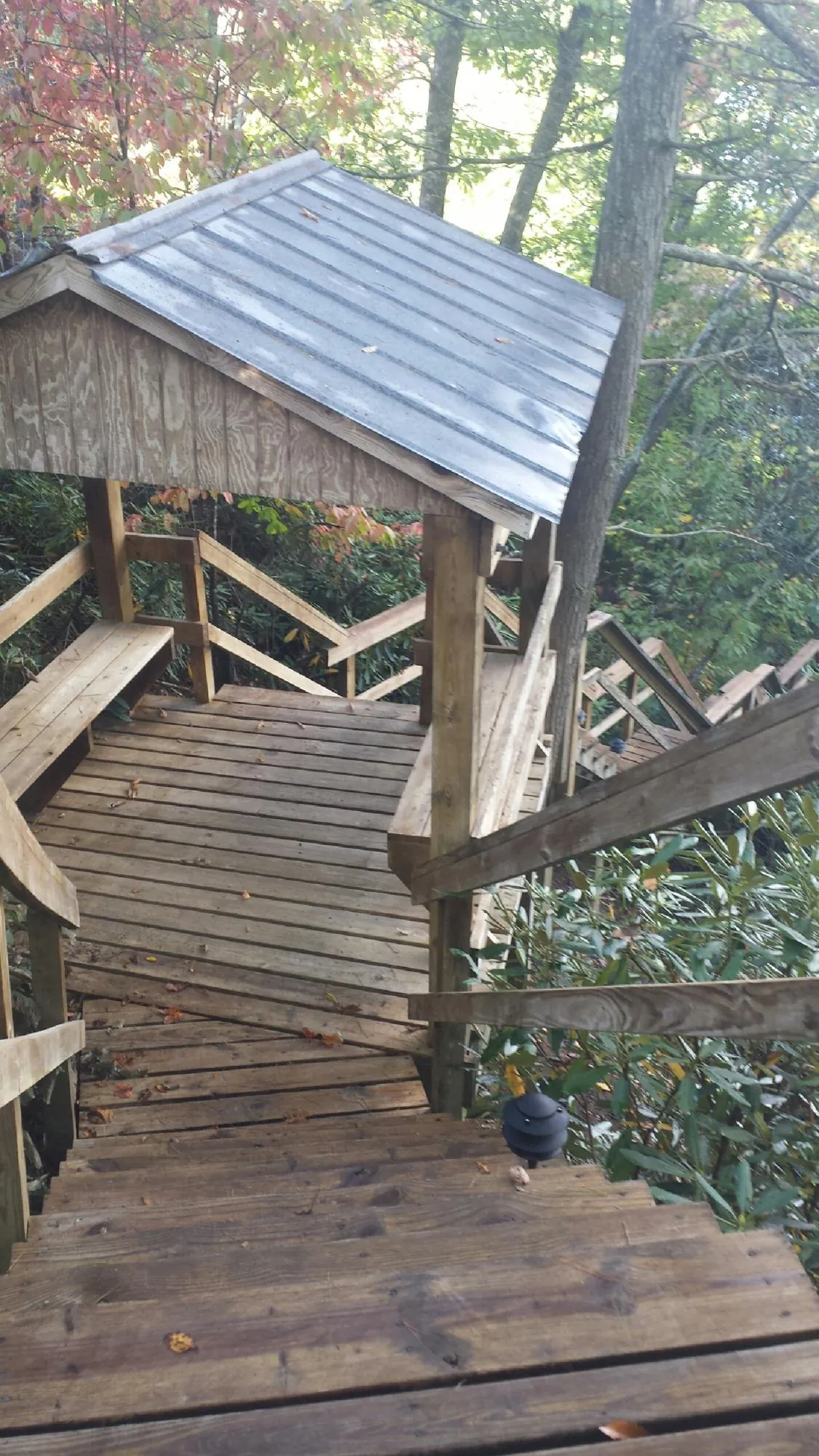 Metal roofed shelter over wooden steps on a wooded walkway — Skylight Repair & Installation work by our crew in Loganton