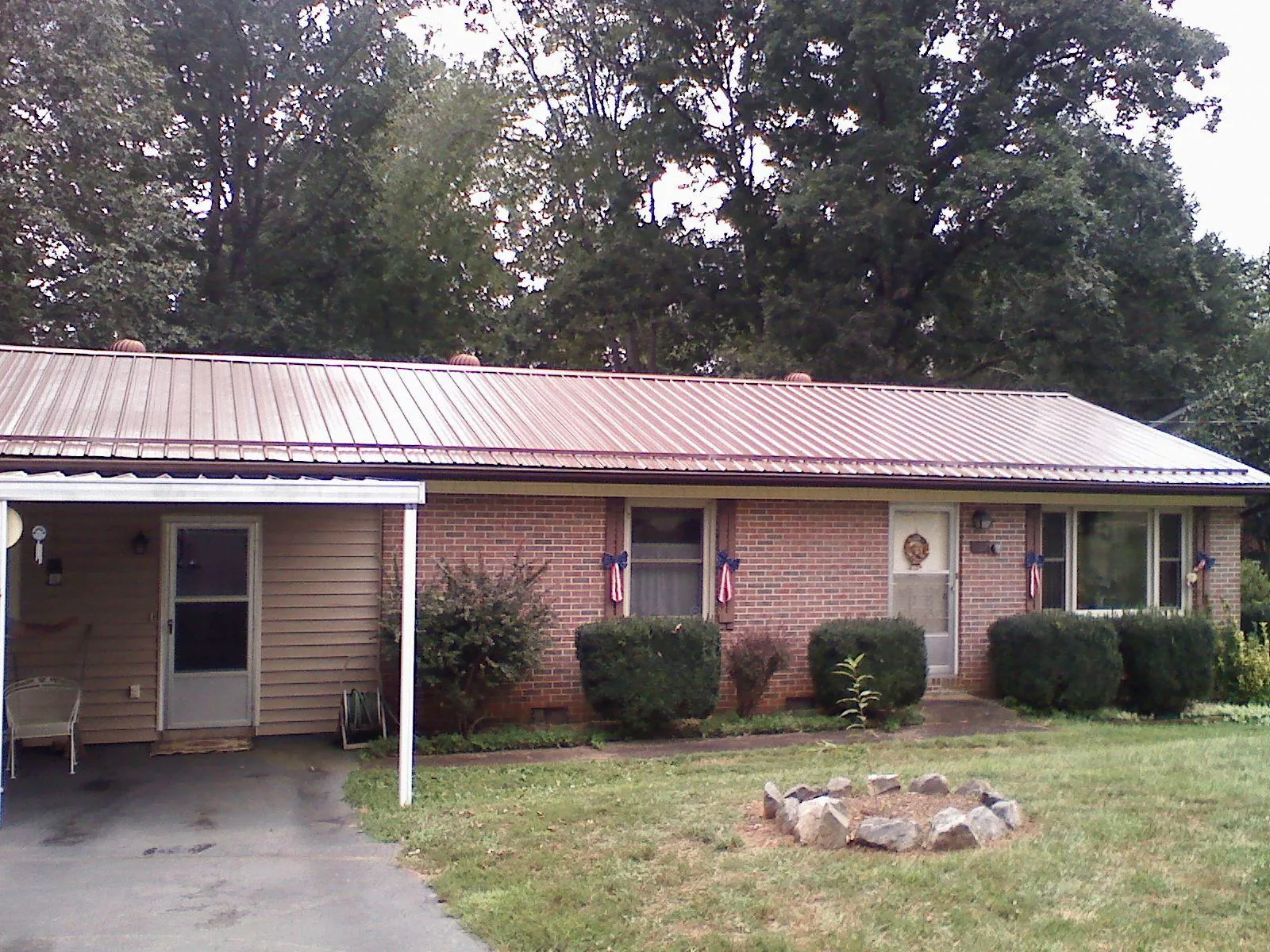 Bronze metal roof and carport on a brick ranch home — Roof Repair work by our crew in Loganton