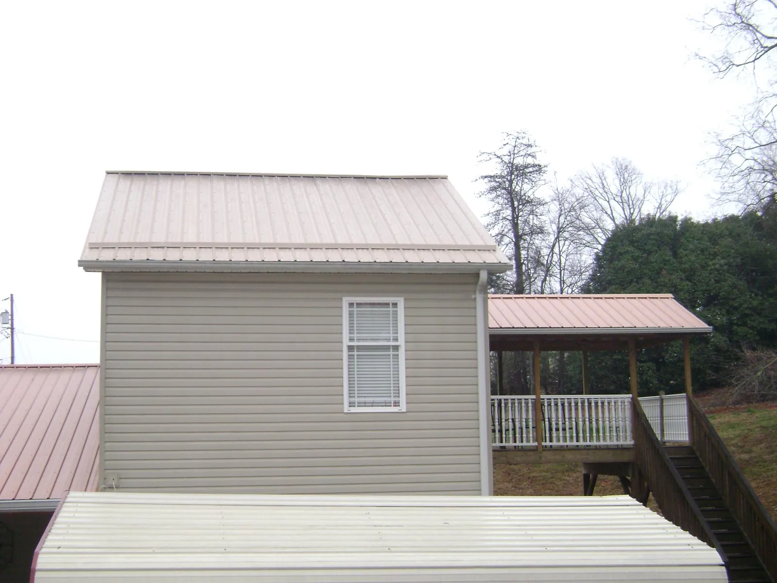 Tan metal roofs on a two story addition and attached porch, from a Roof Replacement job in Loganton