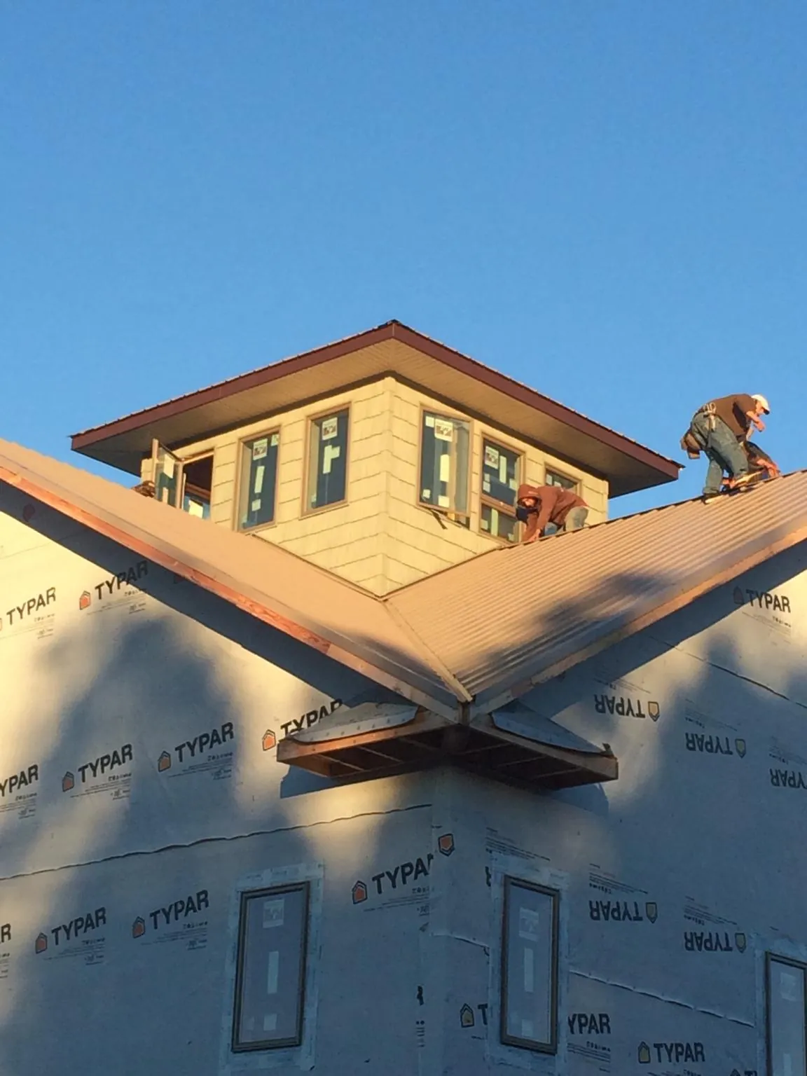 Roofers working around a rooftop cupola on a new metal roof at sunset — Roof Waterproofing in Loganton by Roofing Brothers